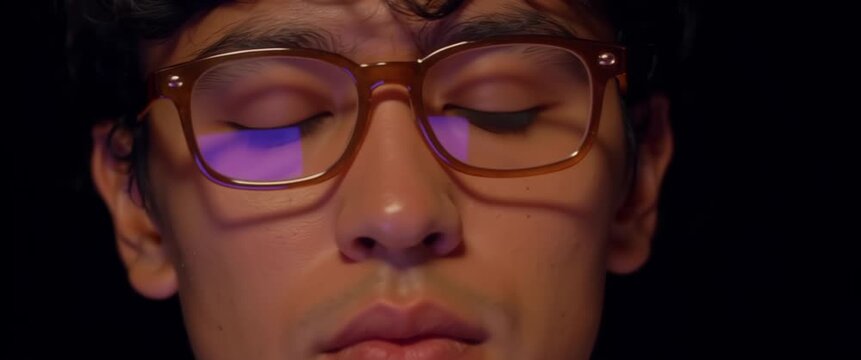 Adult with amber glasses looking aside in violet screen light