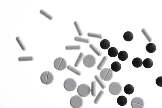 Various white and black tablets, capsules, pills and drag&eacute;es against a white background, Germany