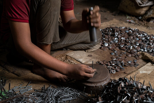 Dhaka, Bangladesh - 07 October 2026: View of a worker manually assembling metal nails in a small workshop.