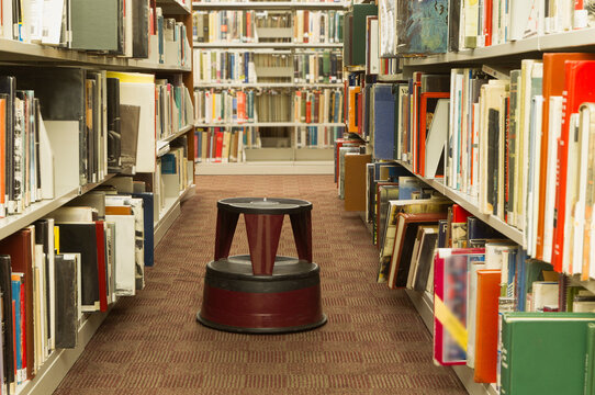 Library Stool Between Bookshelves Filled with Books