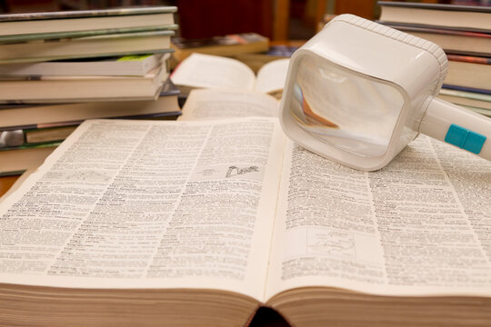 Magnifying Glass on an Open Dictionary in a Library