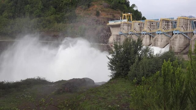 Horizontal stock footage of massive hydroelectric dam releasing powerful white water torrent