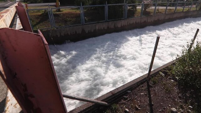 Vertical stock footage of rapid white water flow in concrete channel covered with safety wire mesh