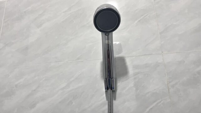A collection of assorted microfiber floor mops organized against a grey marble tile wall background. A landscape close-up view showcasing green, purple, and blue household cleaning tools 