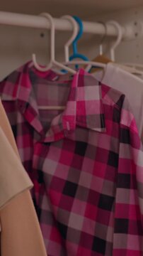 Pink Plaid Shirt on Hanger in Home Wardrobe, Hands Browsing Clothing on Rail and Carefully Handling Blue Garment, Black and Gray Fabric Among Colorful Everyday Closet Selections