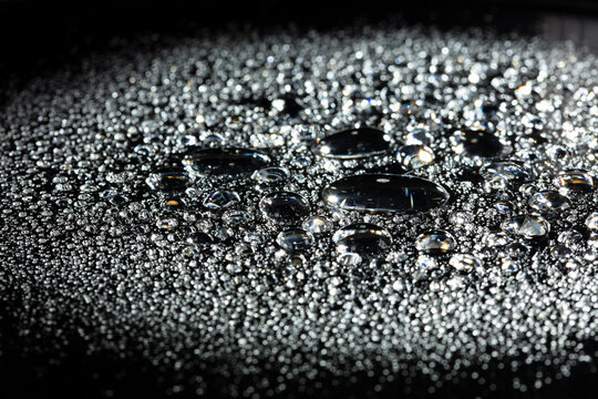 Morning Dew Pure water droplets on a dark surface tension. Water drops rolling off waterproof coating surface tension physics detail clean background, Macro Photography