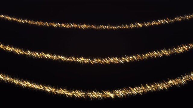 Gold Christmas tinsel garlands swaying and glinting on dark, 4K loop