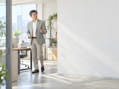 ビジネスイメージに最適な明るいオフィスで身振りを交えて説明する上品な男性 柔らかな自然光と右側の広いコピースペース