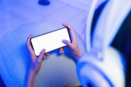 Hands holding smartphone with blank screen while playing mobile game, online gaming and digital entertainment concept.