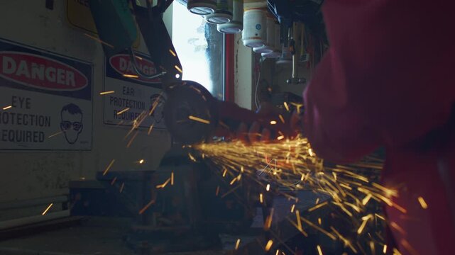 Ski patrol worker uses power grinder on equipment at workbench inside repair shed