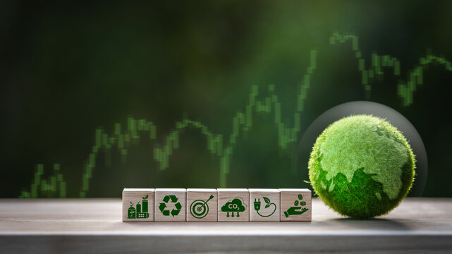 Wooden blocks and environmental icons, accompanied by a globe and a rising stock market graph, represent sustainable investment, financial growth, green business, and global economic progress.