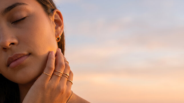 Woman in profile with closed eyes touching face golden hour light
