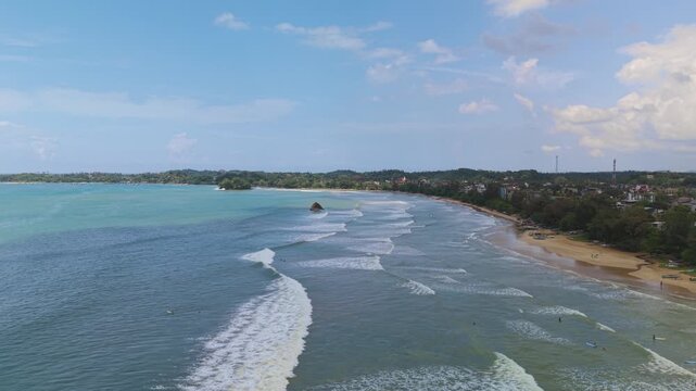 Weligama bay ocean waves towards great polo and little bolo islands with fishing harbor in distance in sri lanka.