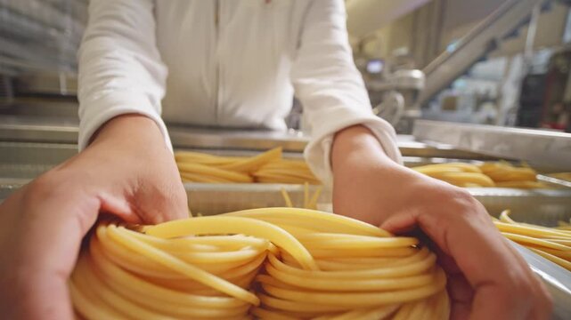 A worker lowers two handfuls of long pasta into a clear tray and shapes them into a neat bundle on a production line.