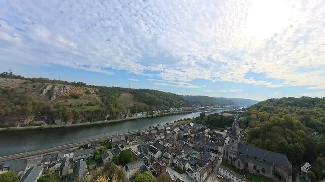 Panning shot revealing the valley town of Dinant along the Meuse River with its historic houses, collegiate church, and prominent limestone cliffs. Crevecoeur ruins