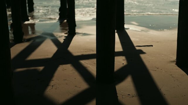 Waves crashing on the shore between the wooden pier columns