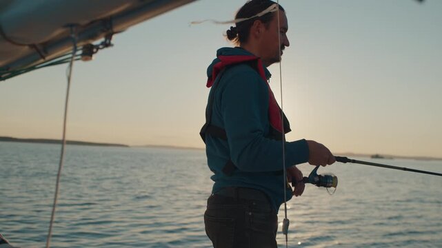 Amateur angler fishing from the sailing boat and casts the lure