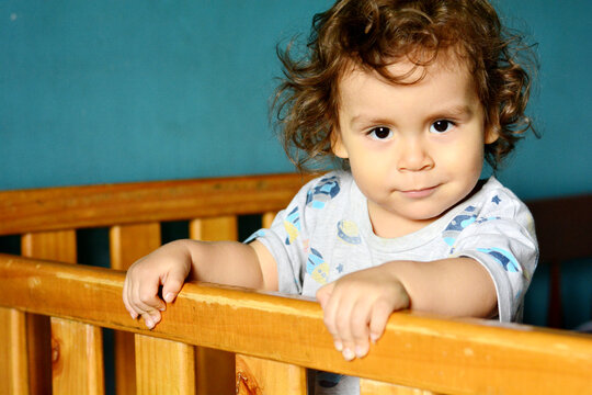 Confident toddler in the crib with slight smile.