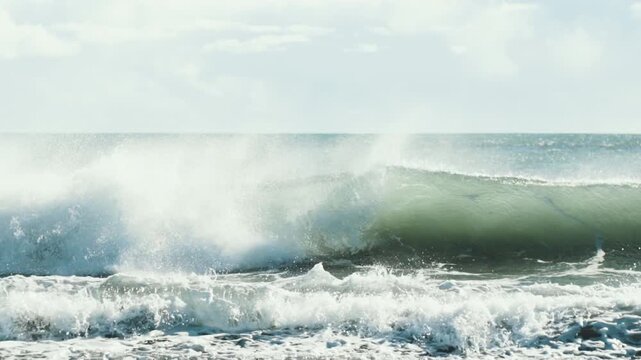 Big ocean wave breaking onto a shingle beach in Iceland slow motion