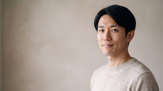 柔らかな光の中で穏やかに微笑むセーター姿の若い男性 | 自然な表情
