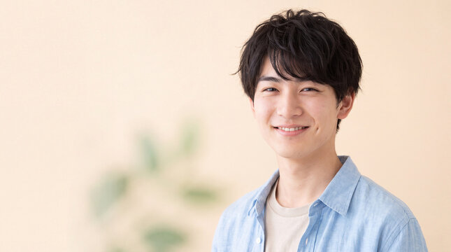 明るい背景の前で人懐っこい笑顔を見せる爽やかな若い男性 | 自然な笑顔