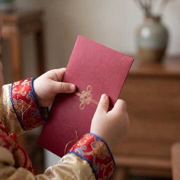 Young child holding an elegant red envelope with decorative pattern  