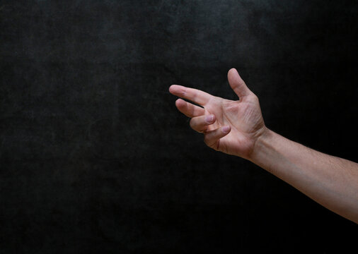 Man's right hand is extended upwards against a dark background