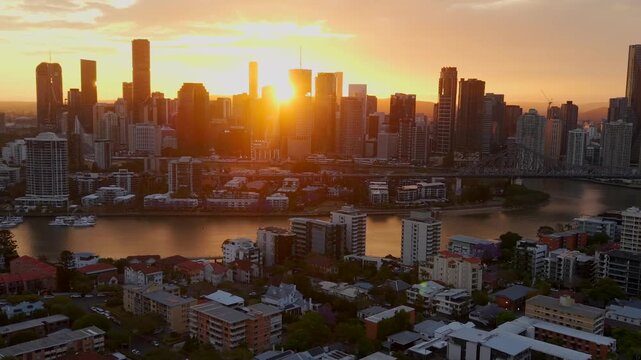 Aerial pull back from Brisbane skyline with setting sun between towers