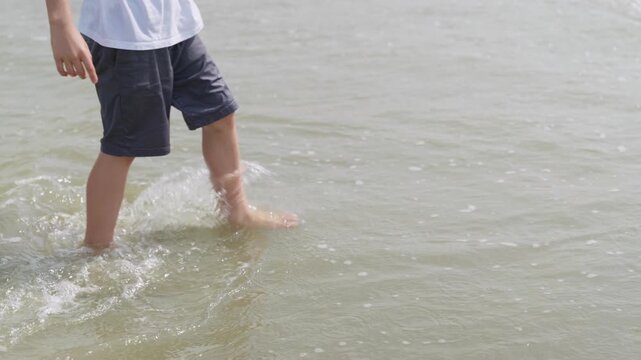 Close-up of a boys legs splashing through shallow sea water slow motion an unrecognizable child