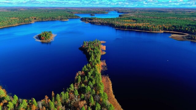 Aerial view of dense green forests surrounding a serene blue lake with small islands