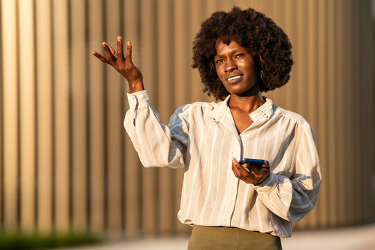 Businesswoman expressing confusion gesturing with smartphone outdoors