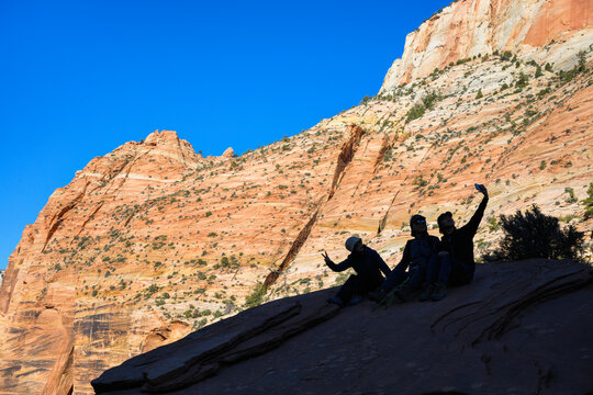 Tourists taking selfies in silhouette on the red rocks. Canyon Overlook Trail at Zion National Park. Utah. USA.