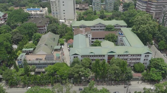 Panoramic Aerial City Landscape with Modern Buildings, Lush Green Trees, Urban Infrastructure and Hazy Hills in the Background