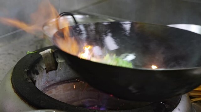 Close-up of a Chinese-style stir-fry with a wok over high heat, tossing and spitting flames.