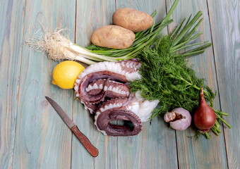 Large octopus tentacles with vegetables on a wooden table close-up © TETYANA