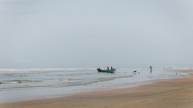 Mandrem beach fishing boat ocean waves and people in Goa India for