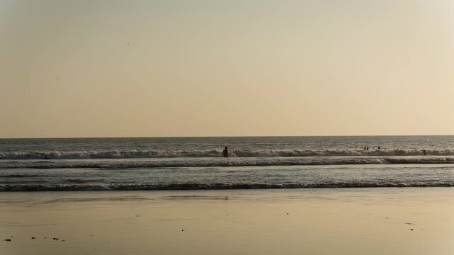 Mandrem beach sunset with ocean waves people swimming and golden