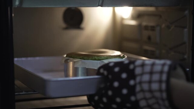 Woman putting Matcha Cake mixture inside hot oven for baking 30fps