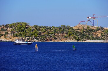 View of the Kavouri peninsula, windsurfers, a yacht and construction equipment, near Vouliagmeni, Attica, Greece © Konstantinos