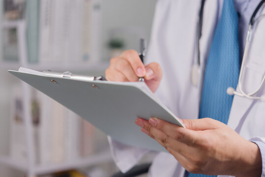 Doctor writing on clipboard while reviewing medical records