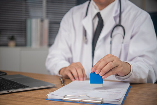 Doctor pressing stamp on medical document at office desk