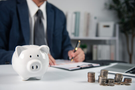 Business professional planning savings with piggy bank and coin stacks