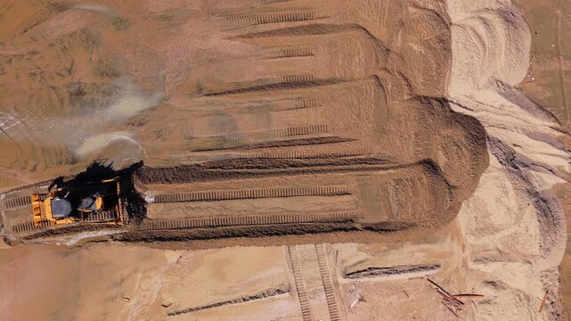 Long Beach, California, USA - October 15, 2026: Top down view of a bulldozer pushing wet sand from the waterline up the beach, raising the shore and building a flood berm after Tropical Storm Rachel.