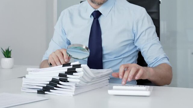 Mature businessman investigating financial documents with a magnifying glass. Performing detailed analysis. Scrutinizing reports