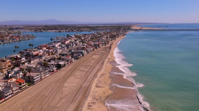 Long Beach, California, USA - October 15, 2026: Long protective sand berm runs along the Peninsula between homes and surf, Alamitos Bay marina on the left, after Tropical Storm Rachel.