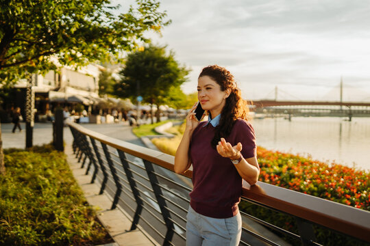 Businesswoman talking on cellphone by river waterfront at sunset