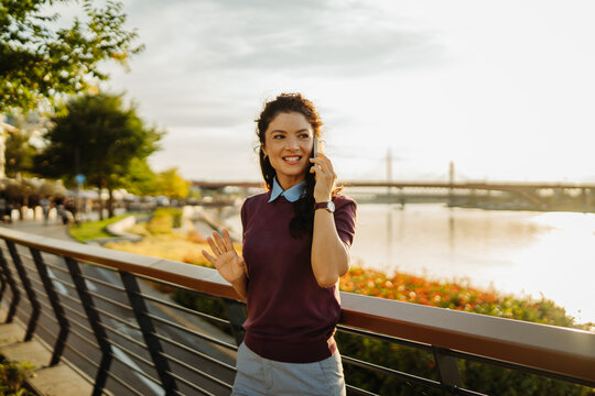 Woman talking on smartphone enjoying urban riverside sunset
