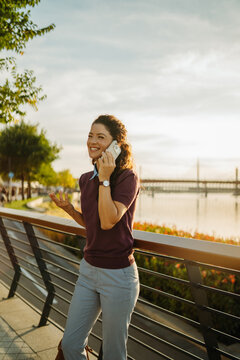 Woman talking on phone along city river promenade