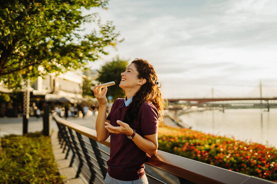 Woman recording voice message on phone by river