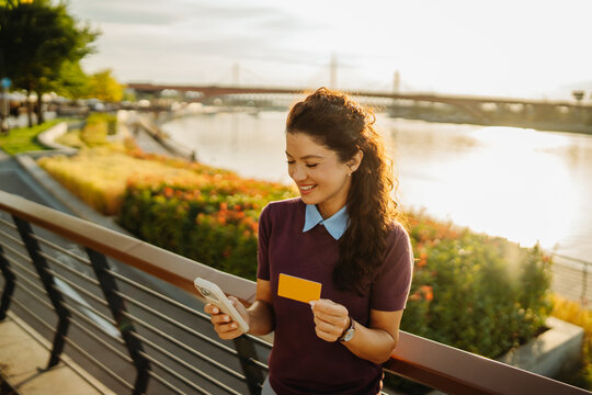 Woman holding credit card and smartphone shopping online